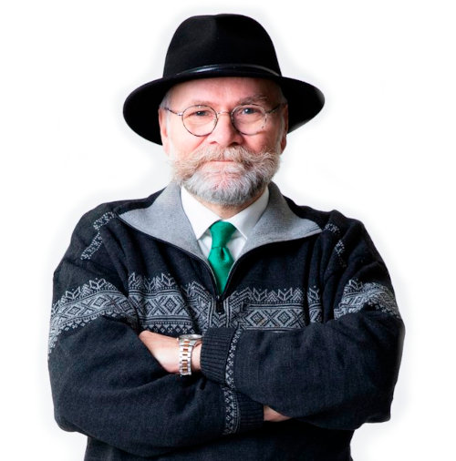 Hattupäinen, harmaapartainen mies hymyilee.